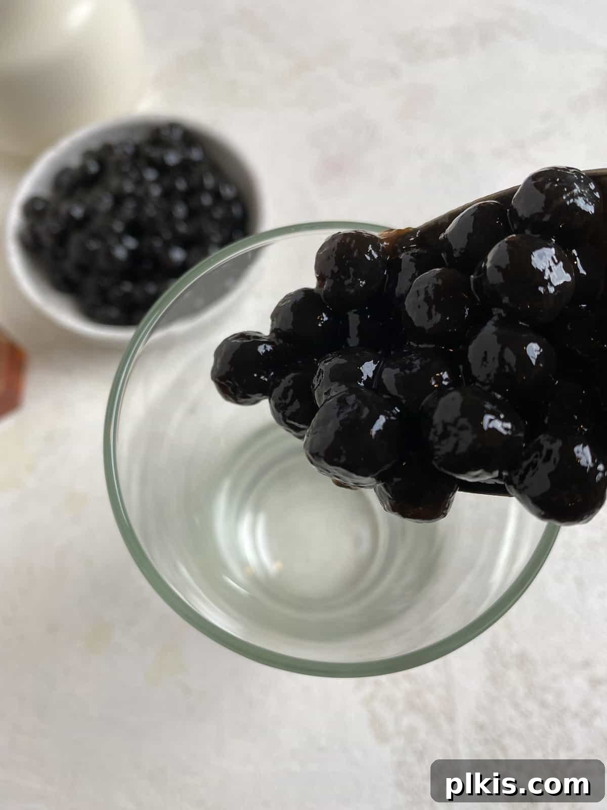 Simple Vegan Boba Bliss 4 Process shot of pouring cooked tapioca pearls into a glass, forming the base of an Easy Vegan Bubble Tea.