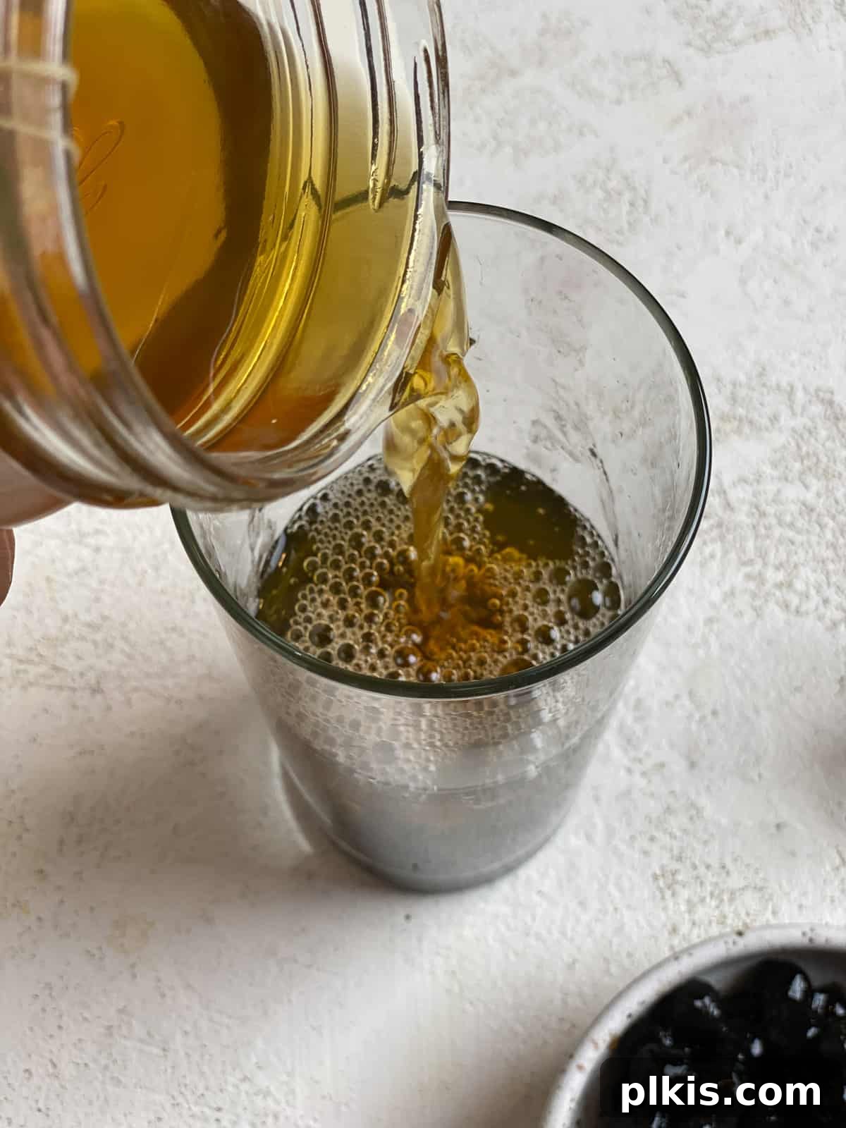 Simple Vegan Boba Bliss 5 Process shot of pouring freshly brewed black tea into a glass already containing tapioca pearls, preparing an Easy Vegan Bubble Tea.