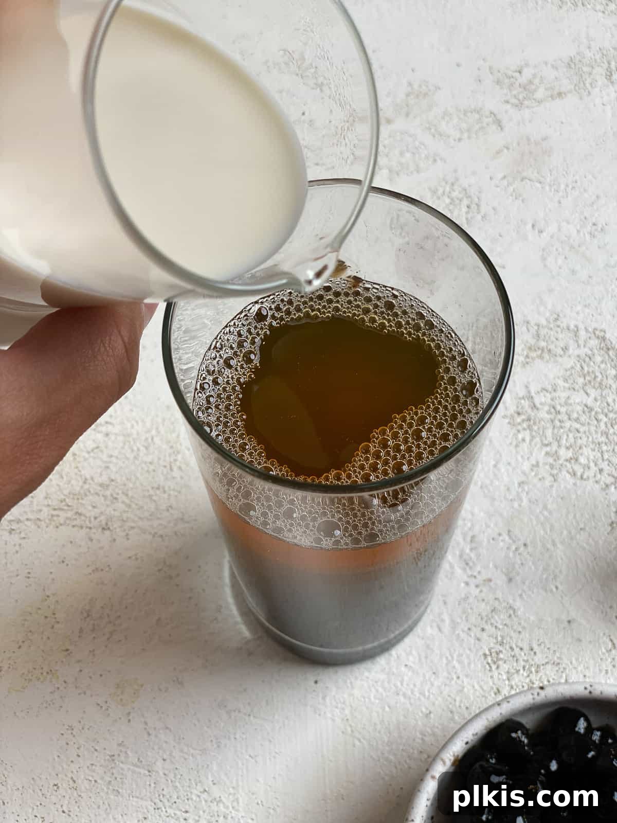Simple Vegan Boba Bliss 6 Process shot of pouring plant-based creamer into a glass with tea and boba, creating the creamy layer of an Easy Vegan Bubble Tea.