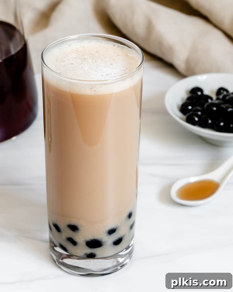 Simple Vegan Boba Bliss 8 A completed glass of Easy Vegan Bubble Tea, showcasing its creamy layers and chewy boba, with all the fresh ingredients artfully arranged in the background.