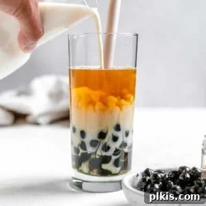 Process shot of pouring boba tea into a glass with ingredients in the background