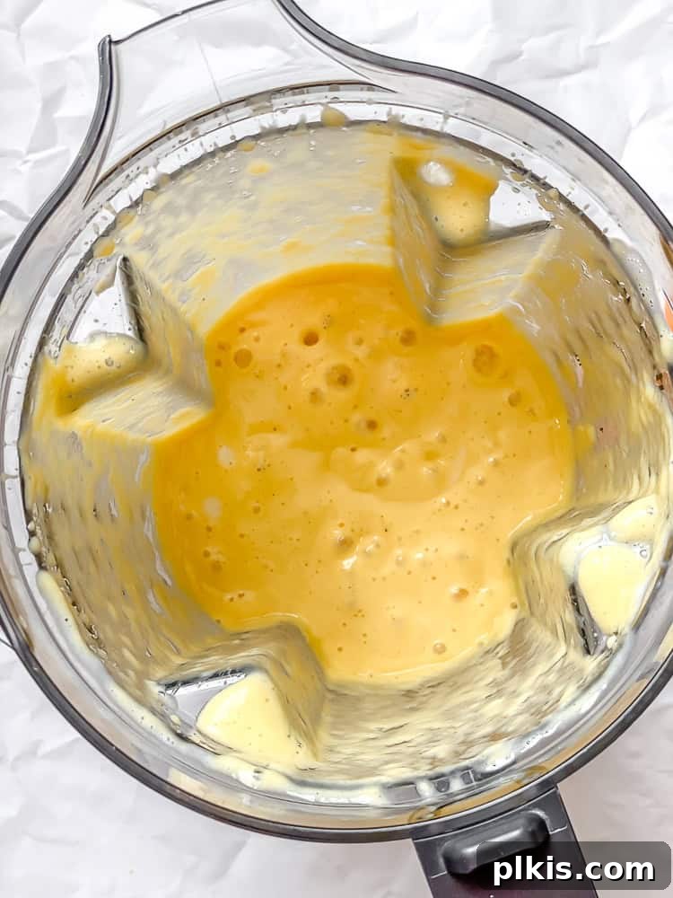 Tropical Glow Smoothie 5 Blender with Mango Orange Smoothie ingredients mid-blend, showing the swirling, creamy mixture inside the container.