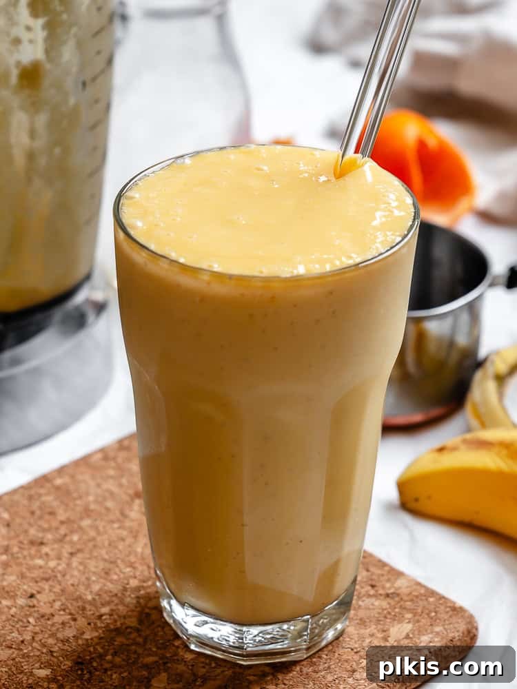 Tropical Glow Smoothie 7 A beautifully garnished Mango Orange Smoothie in a clear glass, showing its appealing texture and color.