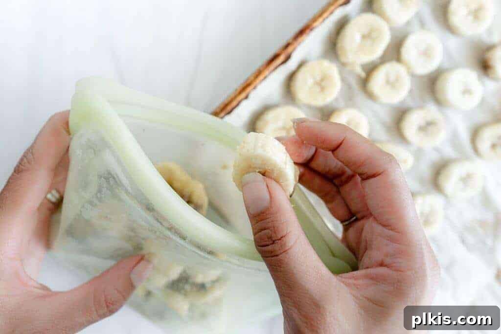 Extend Banana Life: Freezing Made Simple 2 Frozen banana slices being placed in a reusable zipper top bag.