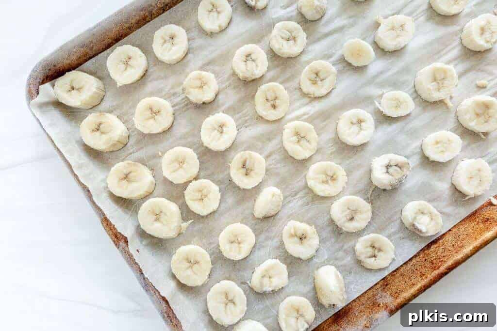 Extend Banana Life: Freezing Made Simple 3 Frozen banana slices on a parchment-lined baking sheet.