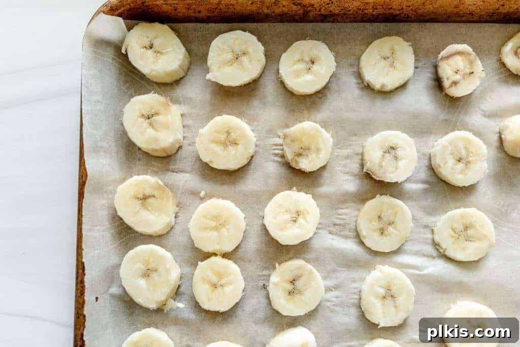 Extend Banana Life: Freezing Made Simple 5 Closeup of frozen banana slices on a parchment-lined baking sheet.
