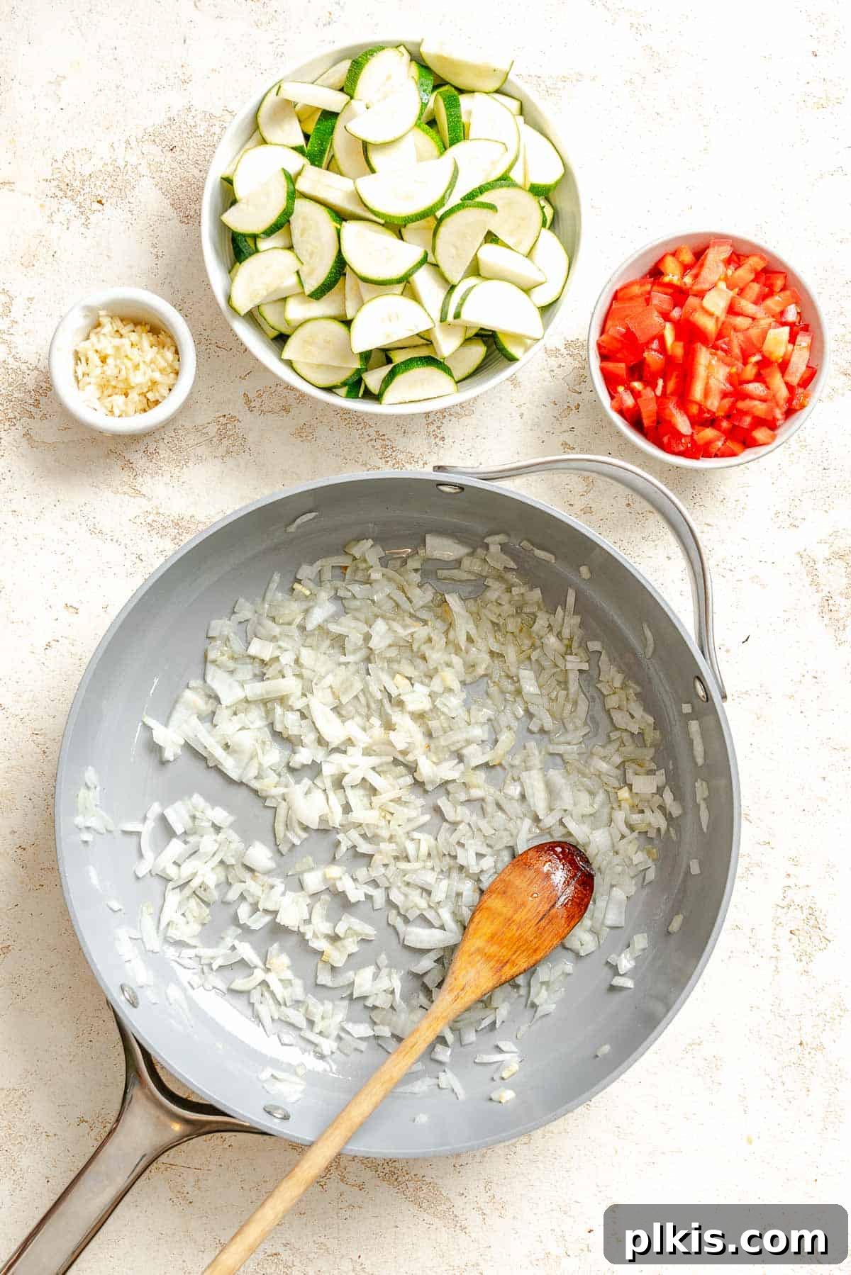 Effortless Calabacitas: A Mexican Zucchini Delight 4 Process shot showing onions cooking in pan with veggies in separate bowls alongside pan.