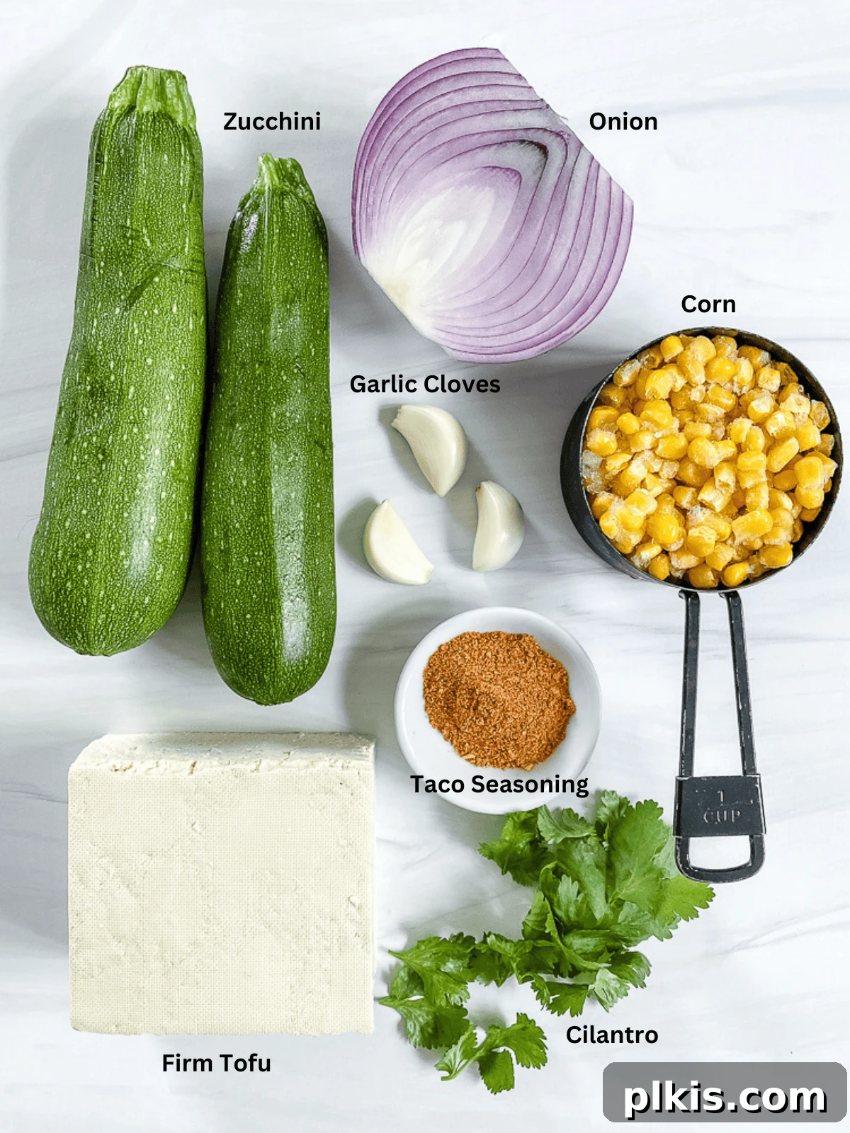 Ingredients for Vegan Zucchini Boats meticulously measured and laid out on a clean white surface, showcasing fresh vegetables and seasonings.