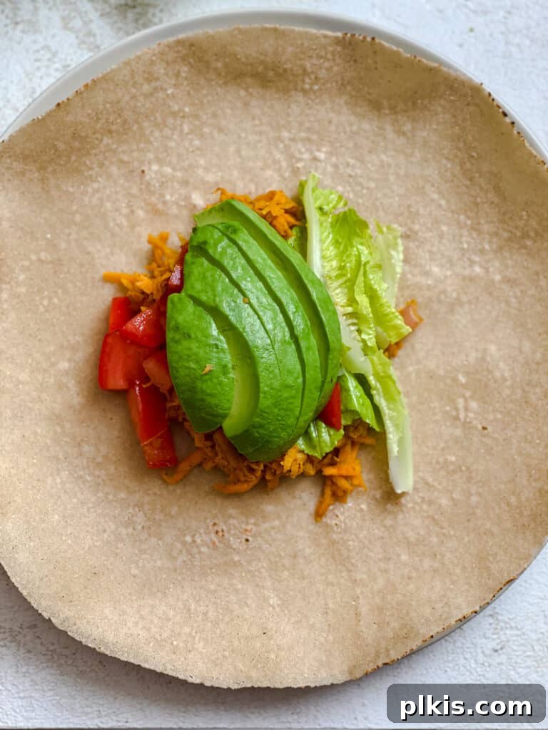 Roasted Sweet Potato and Black Bean Burritos 11 process shot showing added sweet potato mixture and lettuce and avocado and tomato added to tortilla