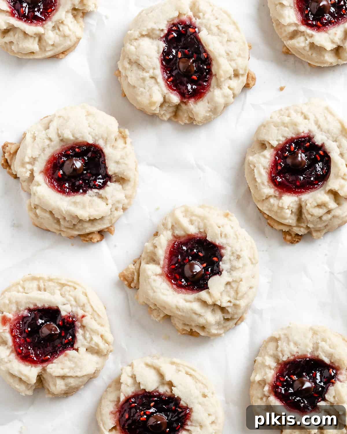 Ruby Raspberry Thumbprint Delights 2 completed Raspberry Jam Thumbprint Cookies scattered on a white surface