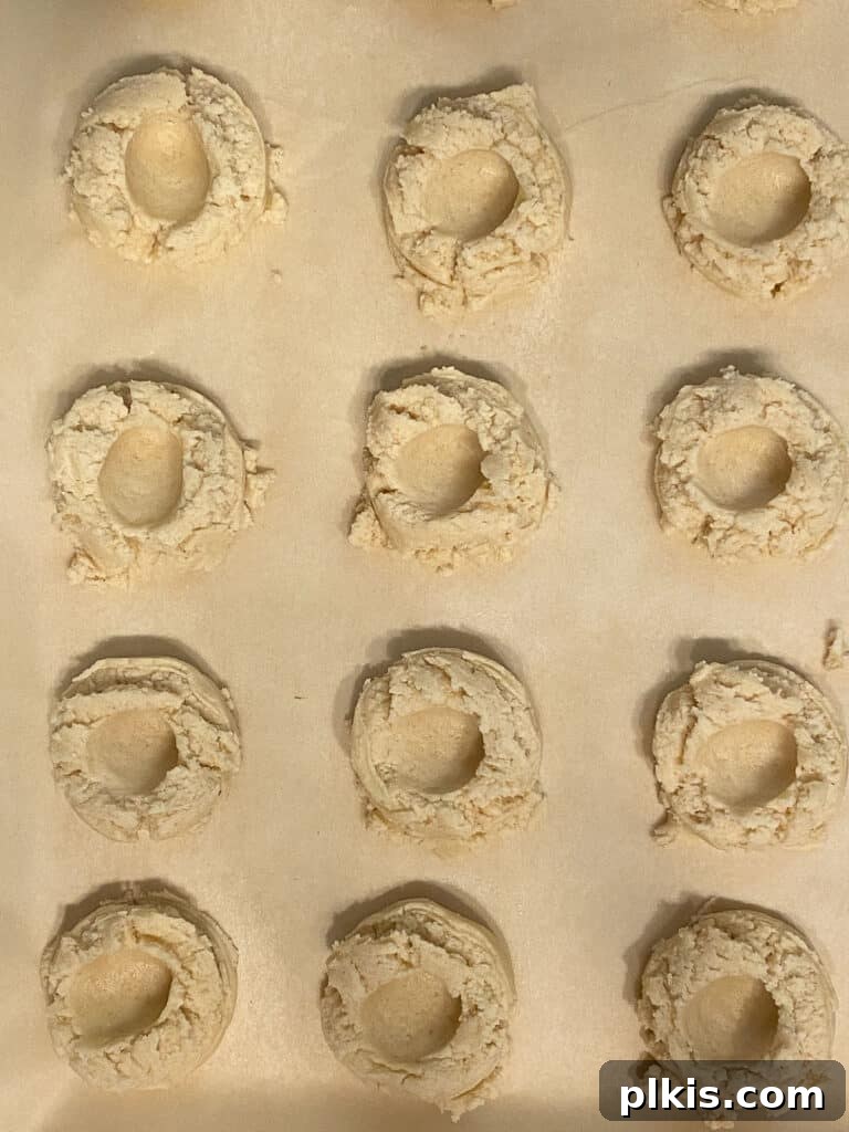 Ruby Raspberry Thumbprint Delights 14 several pre-baked cookies with imprint on baking sheet