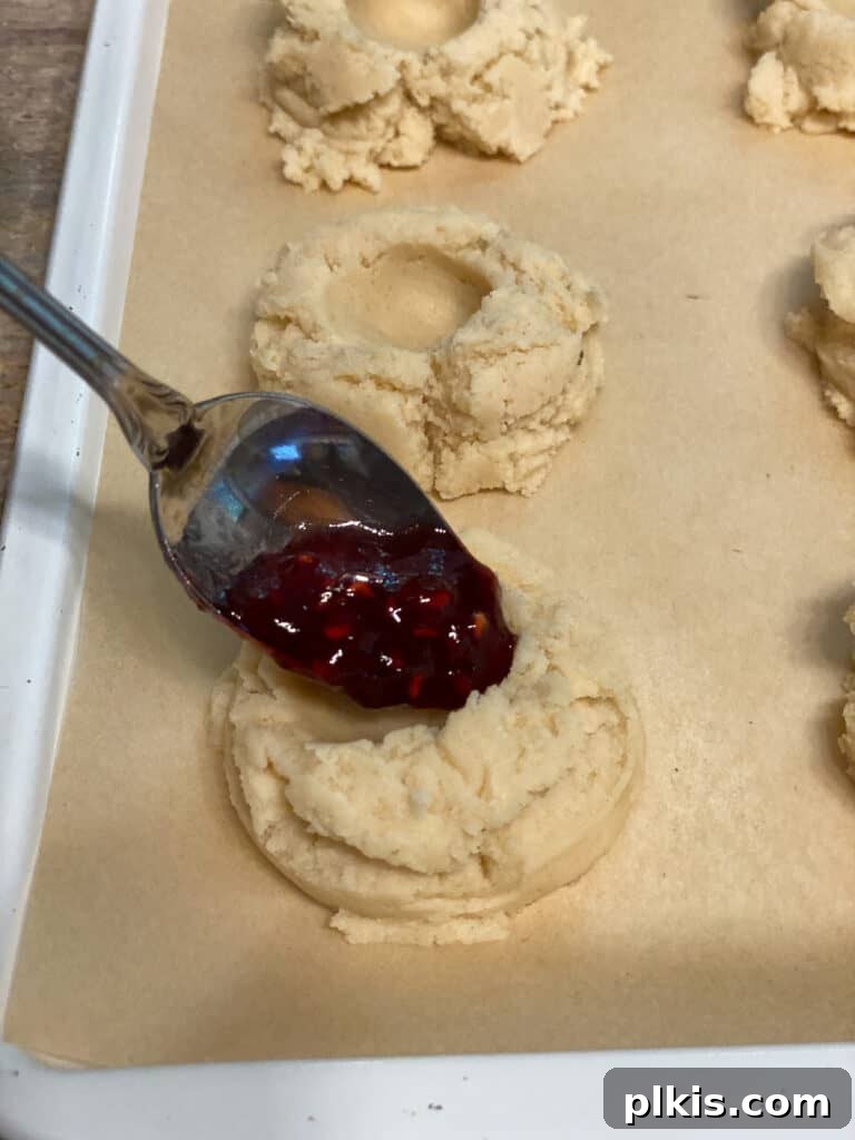 Ruby Raspberry Thumbprint Delights 15 process shot of adding raspberry jam to dent in dough