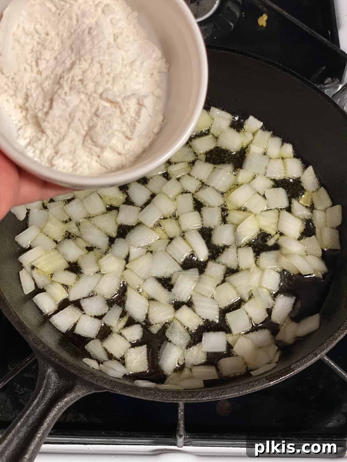 Effortless Plant-Based Gravy 5 Adding flour to a pan with sautéed onions and oil to create a roux, the thickening base for vegan gravy.