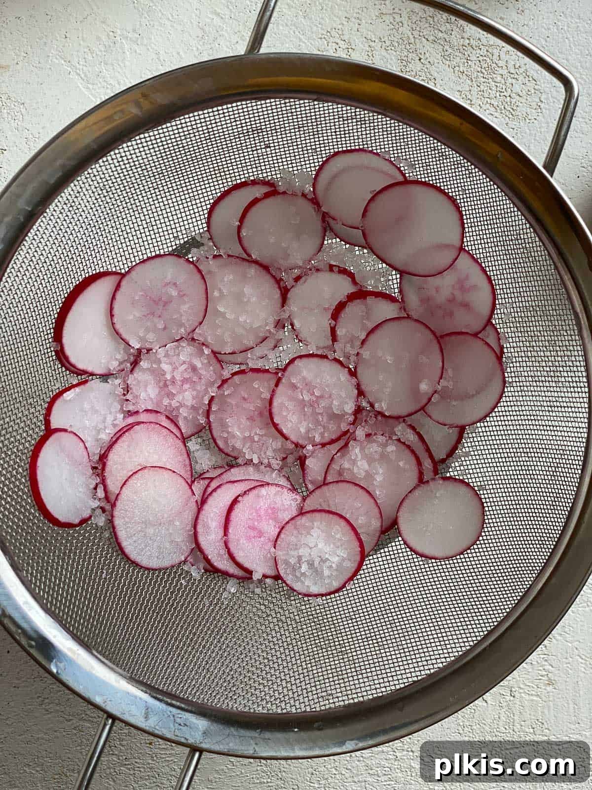 Sugar Snap Peas with Horseradish Fire 5 Salted radishes resting in a small metal strainer, with excess moisture dripping away.