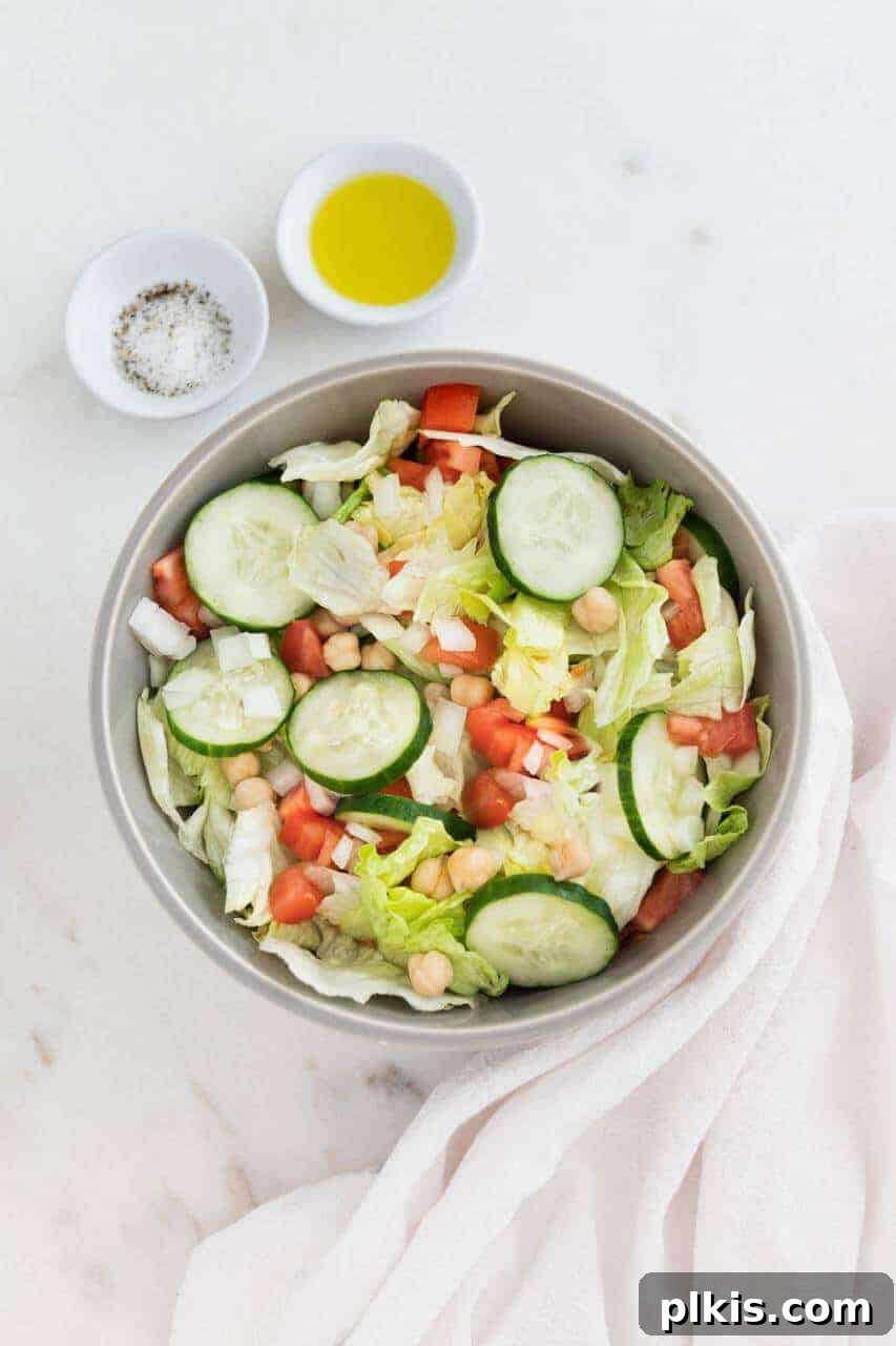 Solo Plant-Based Budget Challenge: Week 1 6 Fresh green salad with cucumbers, tomatoes, and garbanzo beans in a white bowl.