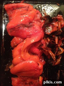 Budget Plant-Based Challenge for Two Week 2 11 A hand gently peeling the blackened skin off a roasted red bell pepper, revealing the soft, cooked flesh underneath.