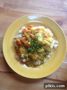 Budget Plant-Based Challenge for Two Week 2 4 Yellow dinner plate featuring a generous serving of brown rice topped with vibrant red lentil curry, garnished with fresh herbs.