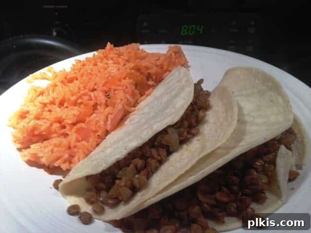 Frugal Vegan Feasts for One: Week 2 Progress 9 Two vegan tacos and a side of Spanish rice on a white plate.