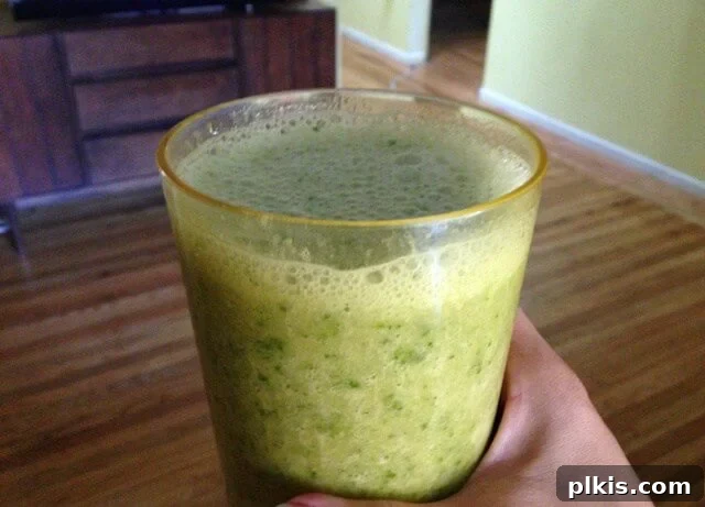 Solo Budget Plant Based Challenge Week 3 13 A hand holding a glass of kale and banana smoothie.