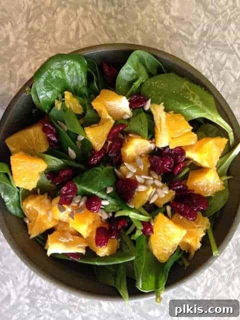 Solo Budget Plant Based Challenge Week 3 3 Bowl of spinach salad topped with peaches, cranberries, and sunflower seeds.