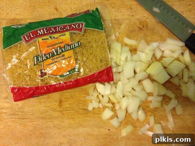 Solo Budget Plant Based Challenge Week 3 10 A bag of spaghetti pieces on a wood cutting board next to diced onion.