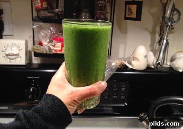 My Solo Budget Vegan Journey: Week 4 13 A hand holding a glass of banana kale smoothie.