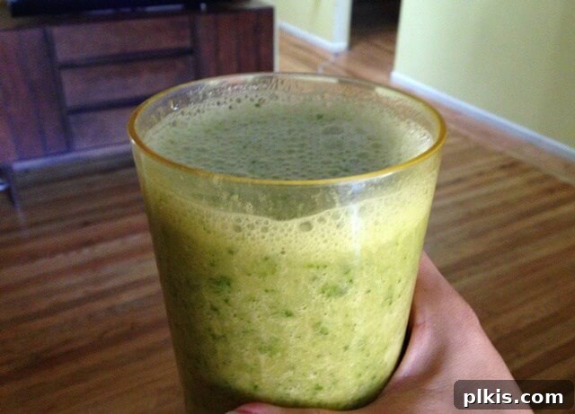 My Solo Budget Vegan Journey: Week 4 5 A hand holding a glass full of banana kale smoothie.