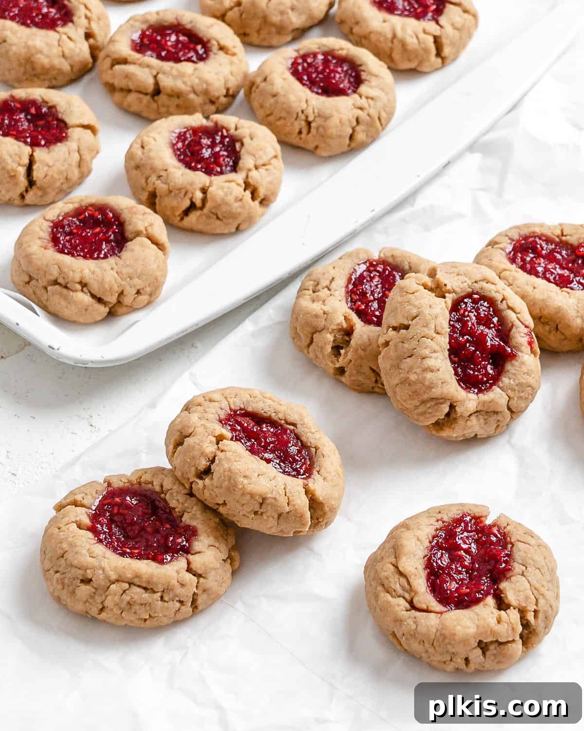 24 Festive Vegan Christmas Cookie Delights 7 Completed Vegan Peanut Butter and Jelly Thumbprint Cookies spread out on a white surface.