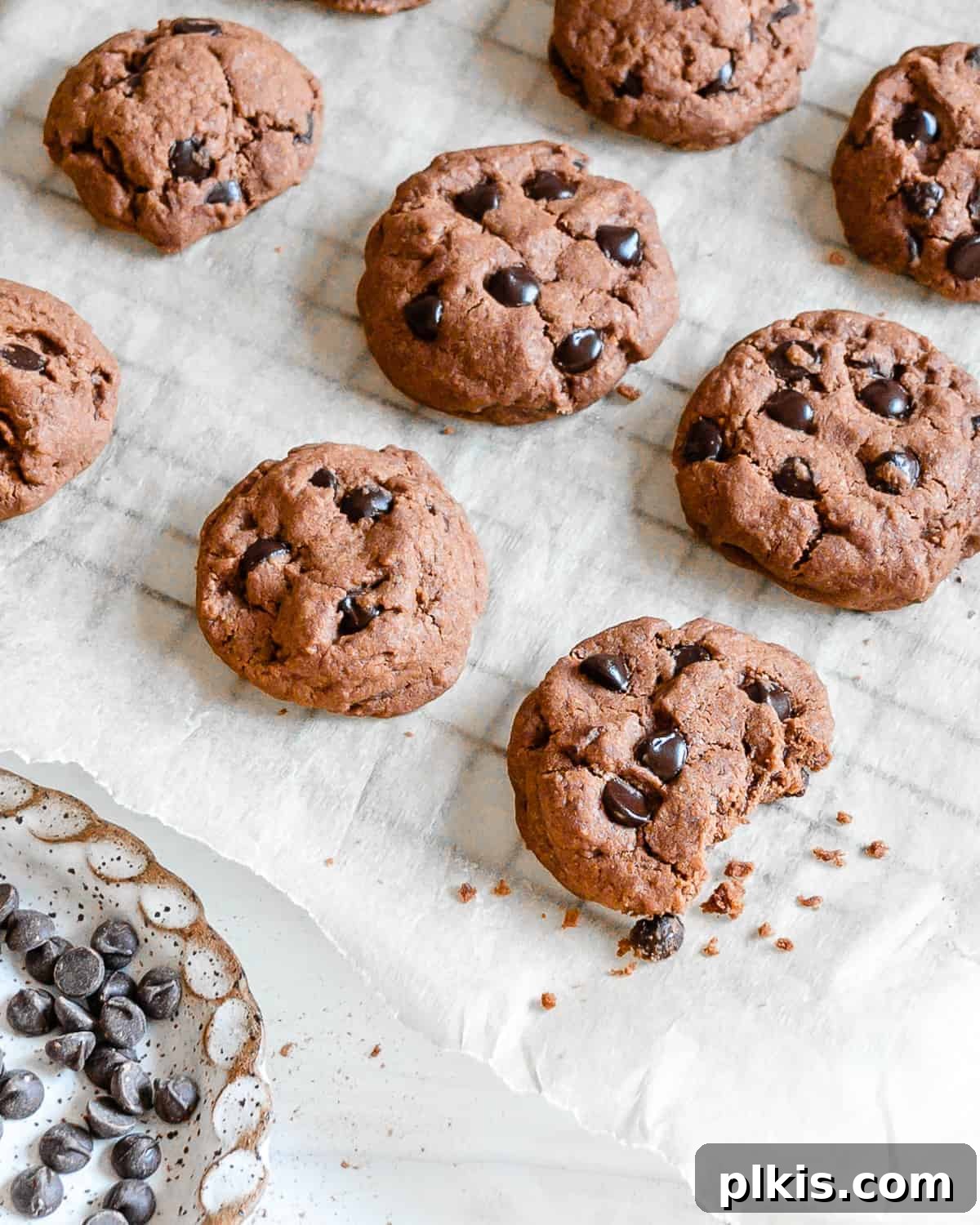 24 Festive Vegan Christmas Cookie Delights 3 Finished Chocolate Peppermint Chocolate Chip Cookies on parchment paper with one halved in the front.