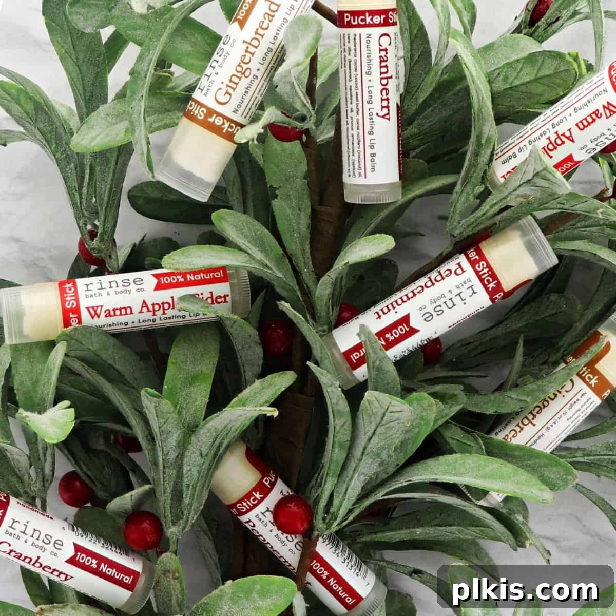 Holiday Gifting Unwrapped Your Essential Picks 15 A collection of Rinse Bath & Body Co. lip balms nestled among green plants.