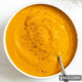 completed Creamy Curried Carrot Ginger Soup in a white bowl against a white background