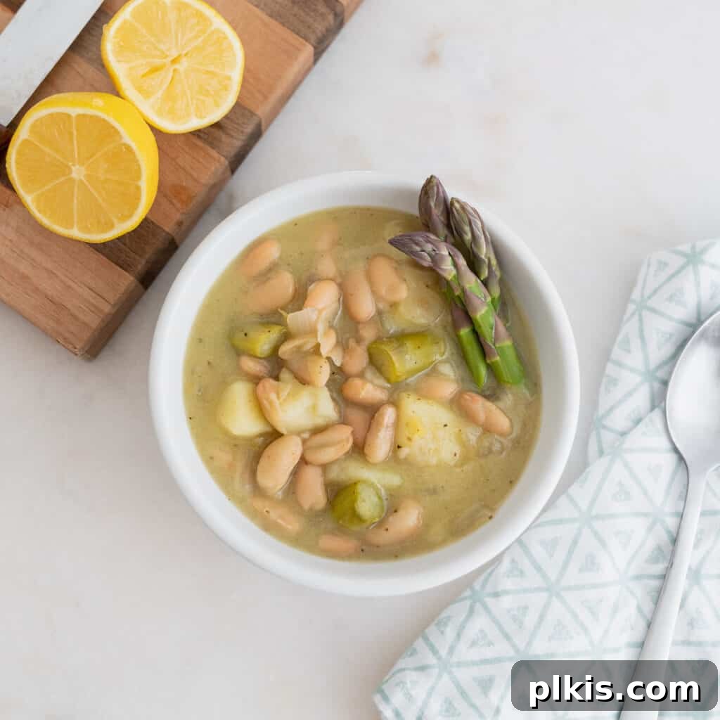 23 Soul-Soothing Vegan Soup Recipes 13 finished creamy asparagus soup separated into two bowls against a white background with lemon on the side