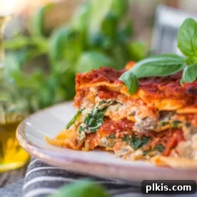 A beautifully plated slice of vegan lasagna, ready to be enjoyed, with vibrant greens blurred in the background.