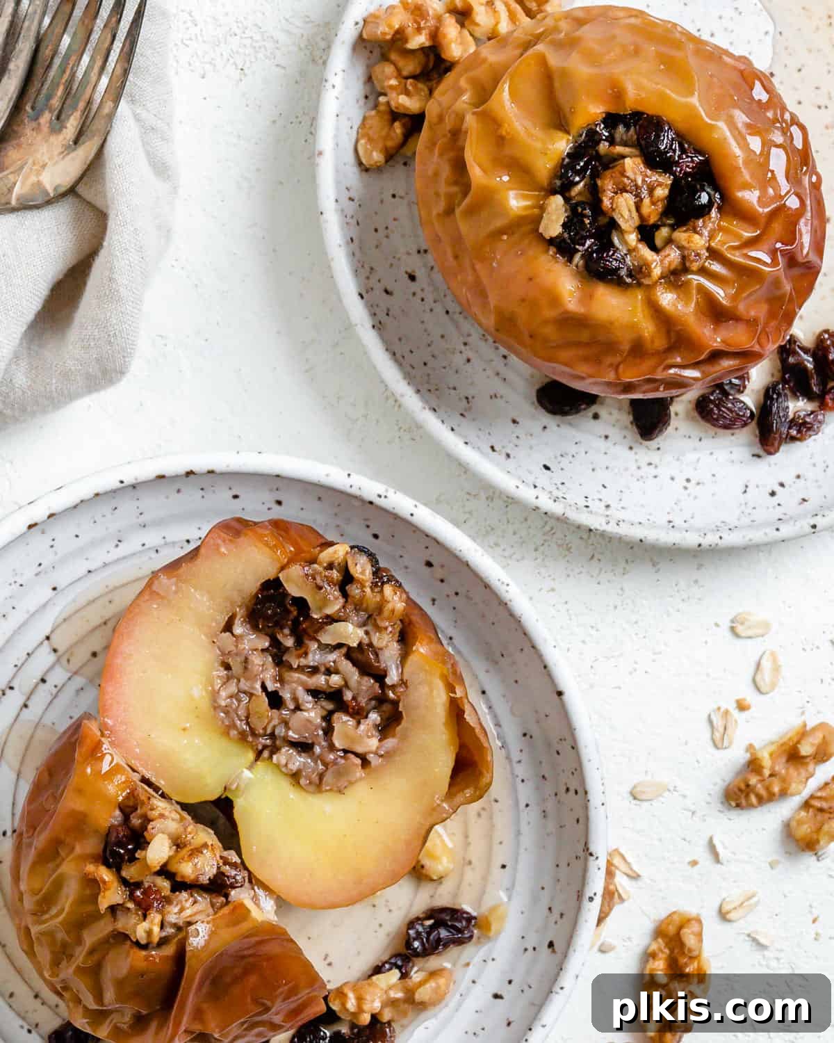 48 Irresistible Vegan Apple Delights 37 Two completed plated stuffed baked apples on white plates against a white background.