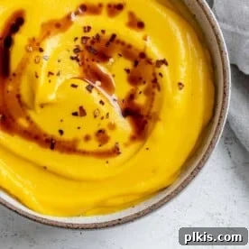 A smaller image of the completed Easy Vegan Pumpkin Soup, perfectly creamy, served on a white surface.