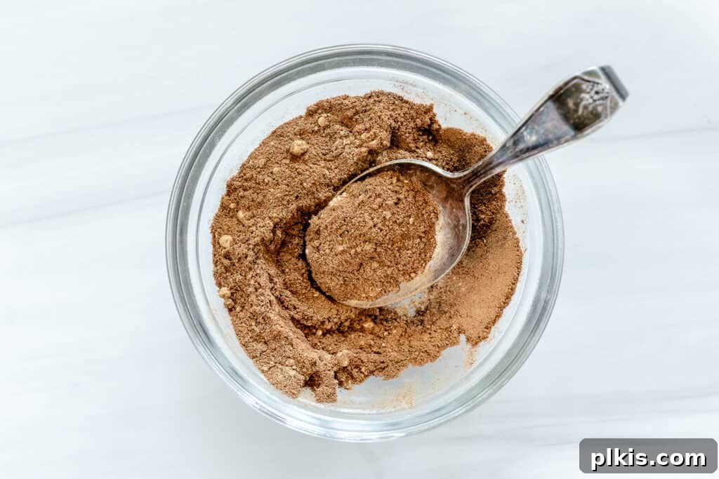 24 Effortless Plant-Based Pumpkin Creations from a Can 25 A glass bowl filled with vibrant homemade pumpkin spice, showcasing its rich color, set against a crisp white background.