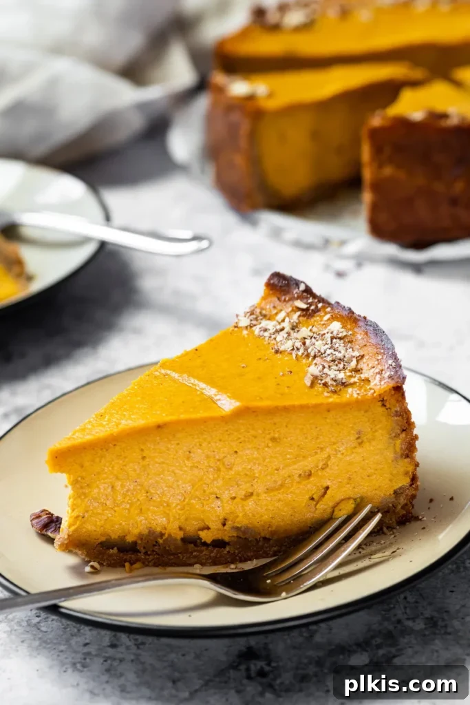 24 Effortless Plant-Based Pumpkin Creations from a Can 35 A perfectly plated slice of oil-free vegan pumpkin cheesecake, showcasing its creamy texture, with the rest of the cake in the background.