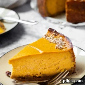 A smaller image of a finished slice of pumpkin cheesecake on a plate, with the rest of the cake in the background.