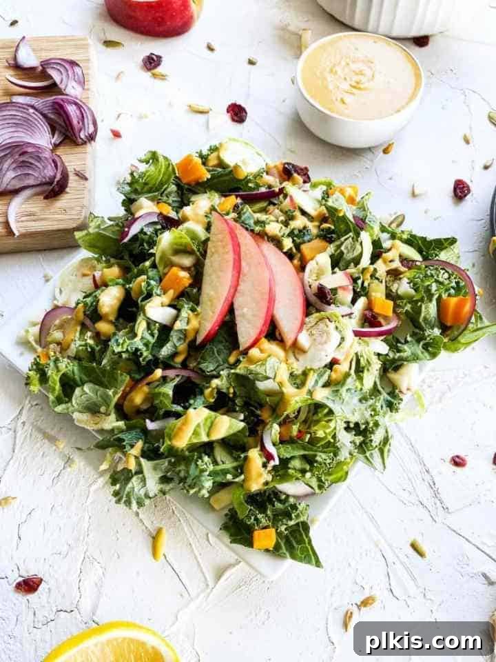 24 Effortless Plant-Based Pumpkin Creations from a Can 39 A beautifully presented pumpkin tahini autumn salad on a white surface, with fresh ingredients scattered in the background.