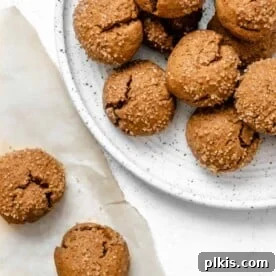 A plate of completed Soft Pumpkin Gingersnap Cookies, with more cookies in the background, showcasing their appealing texture.