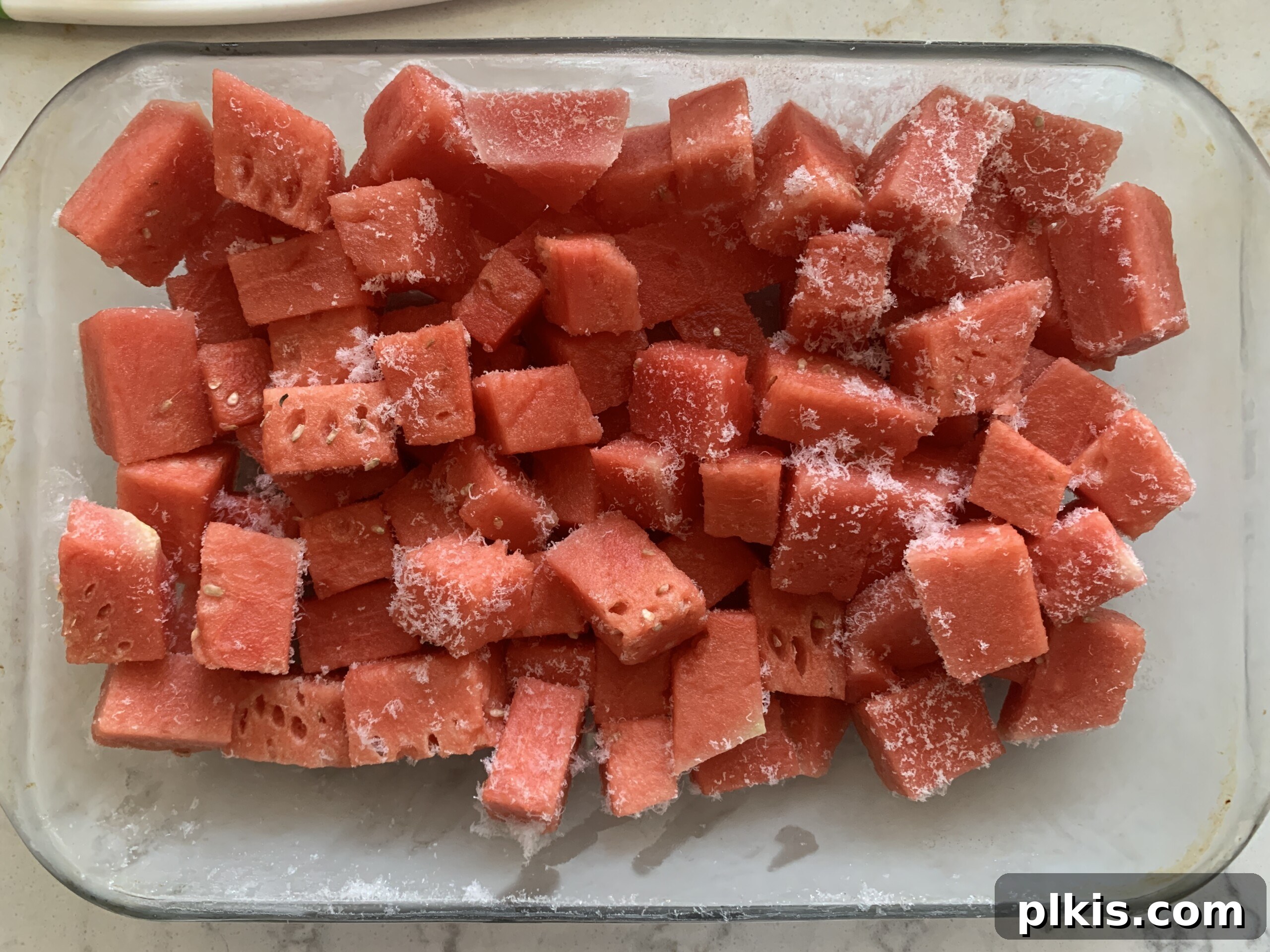 Frosty Watermelon Delight 5 Cubed watermelon pieces spread out evenly on a baking dish, ready for freezing.
