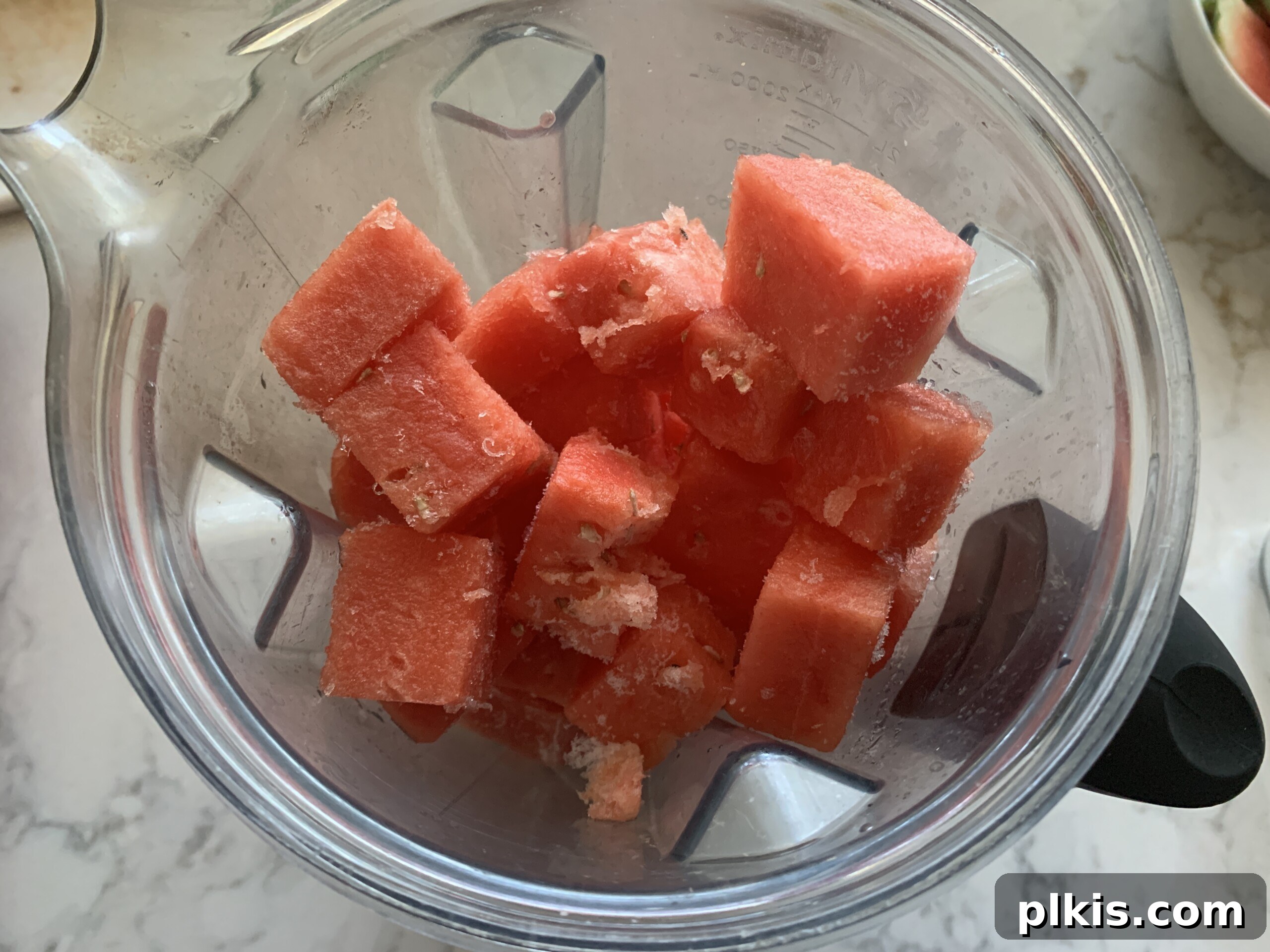 Frosty Watermelon Delight 6 Frozen watermelon cubes and fresh mint sprigs inside a high-powered blender, ready to be blended into a slushie.