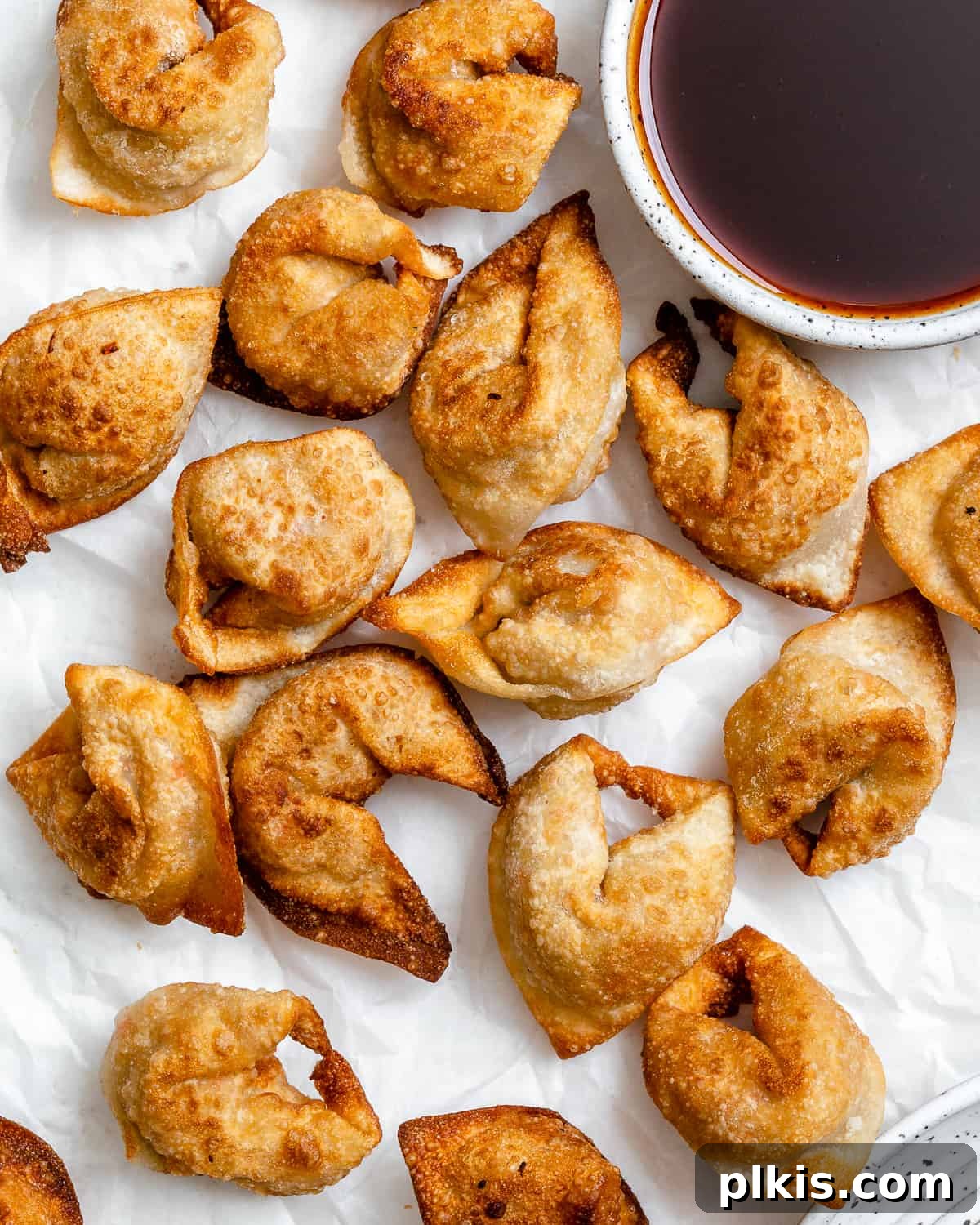 Golden Crispy Tofu Vegetable Wontons Made Two Ways 2 Several completed Tofu Vegetable Crispy Wontons spread out on a white surface, showcasing their golden-brown perfection and inviting texture.