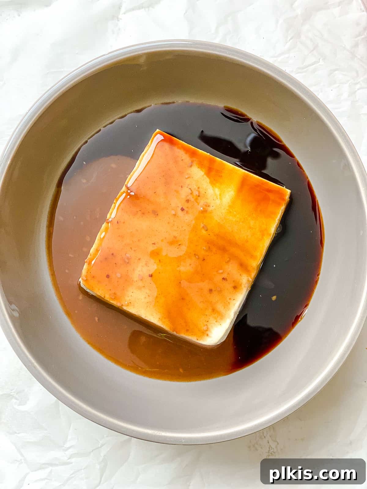 Golden Crispy Tofu Vegetable Wontons Made Two Ways 6 Process shot of crumbled, pressed tofu being added to a bowl containing teriyaki and soy sauce, ready for marination.