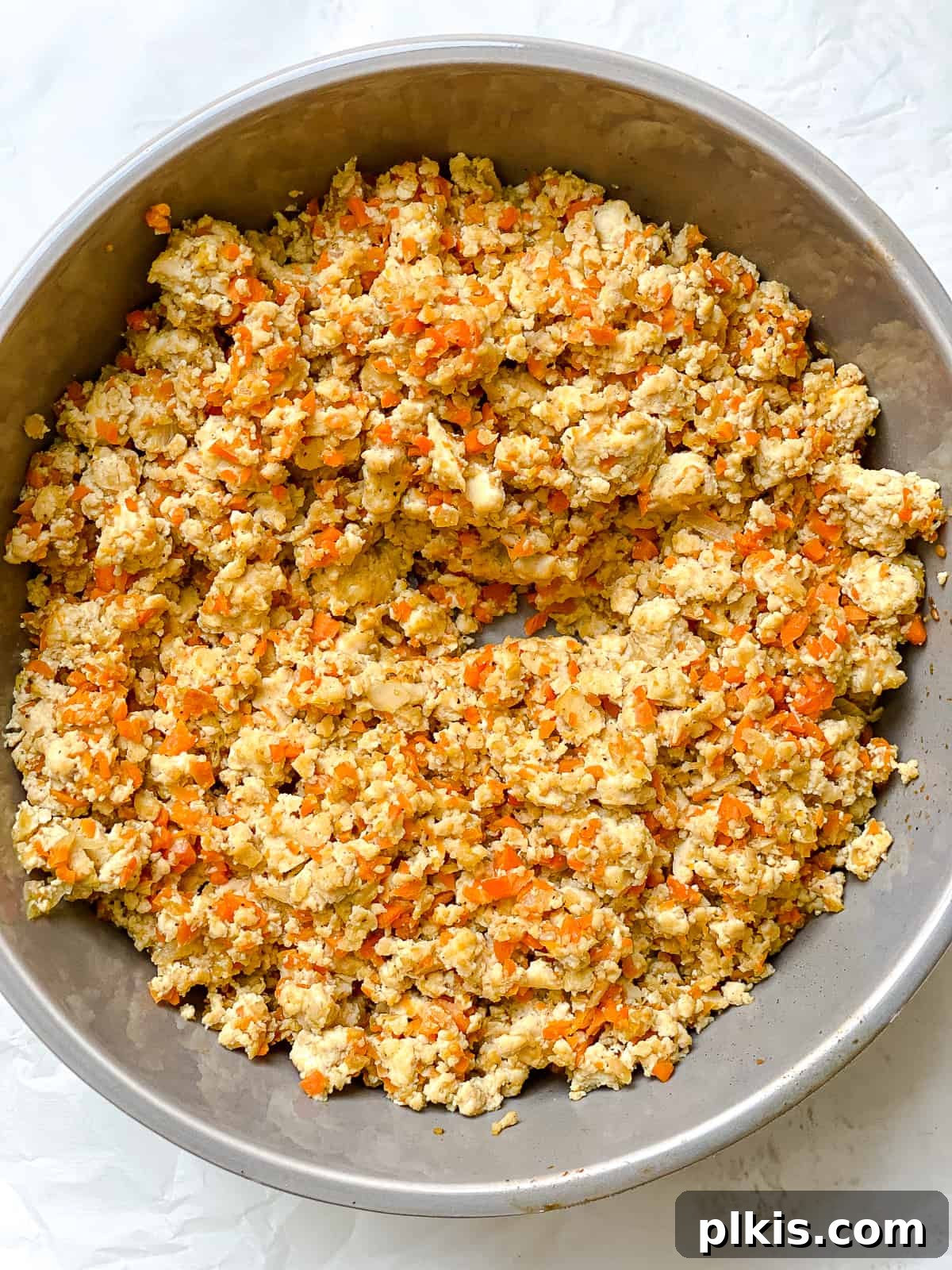 Golden Crispy Tofu Vegetable Wontons Made Two Ways 9 Process shot of the tofu and vegetable filling cooking in a skillet, with a spoon mixing the ingredients until thoroughly combined and cooked.