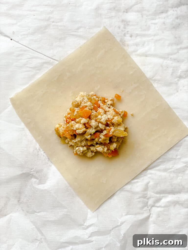 Golden Crispy Tofu Vegetable Wontons Made Two Ways 10 Process shot of a spoonful of tofu and vegetable filling being placed onto the center of a wonton wrapper.