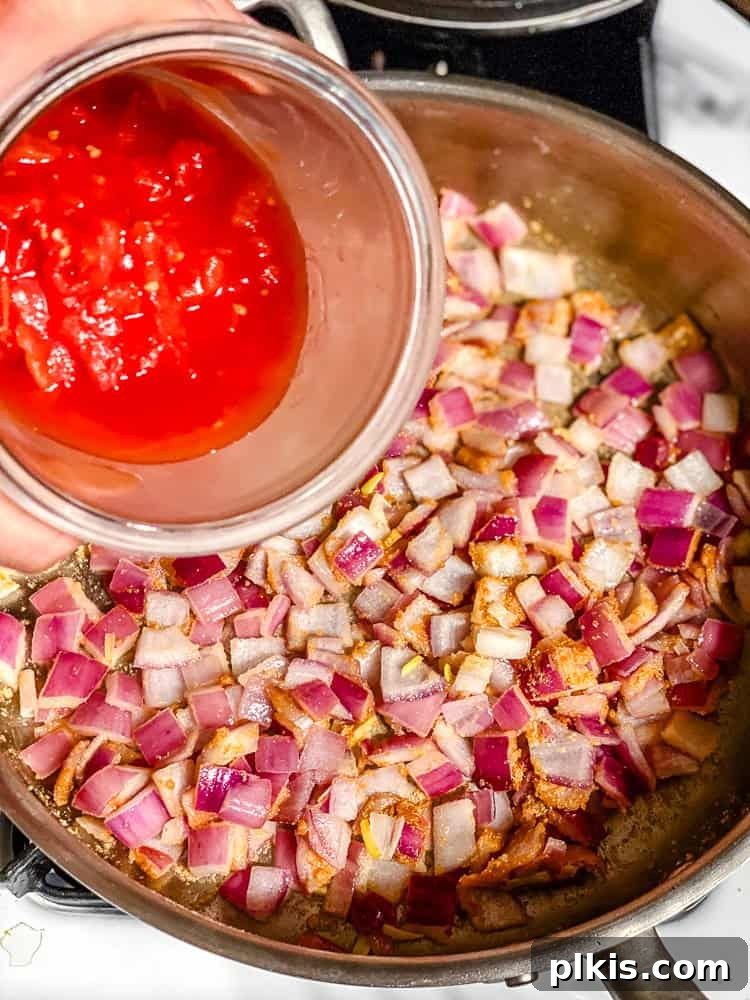 Vibrant 30-Minute Vegan Thai Red Curry 5 Step-by-step image of adding canned diced tomatoes to the sautéed onions in a pan