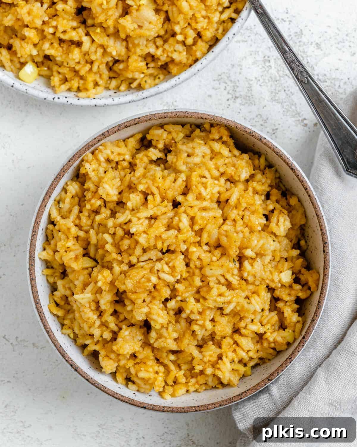 Aromatic Garlic Rice 2 A vibrant bowl of fluffy Golden Garlic Rice, also known as Spanish Yellow Rice, served in a white bowl against a clean white background, ready to be enjoyed as a perfect vegan side dish.