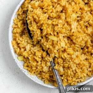 Completed Golden Garlic Rice [Spanish Yellow Rice] in a white bowl against a white background, highlighting its delicious texture and color.