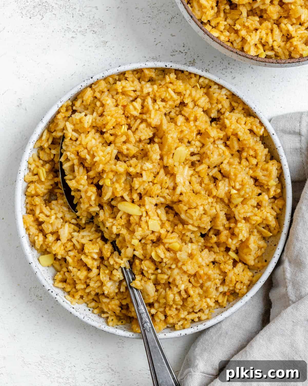 A close-up of a beautifully plated bowl of Golden Garlic Rice [Spanish Yellow Rice], showcasing its fluffy texture and vibrant color, ready to be enjoyed as a delicious side dish.